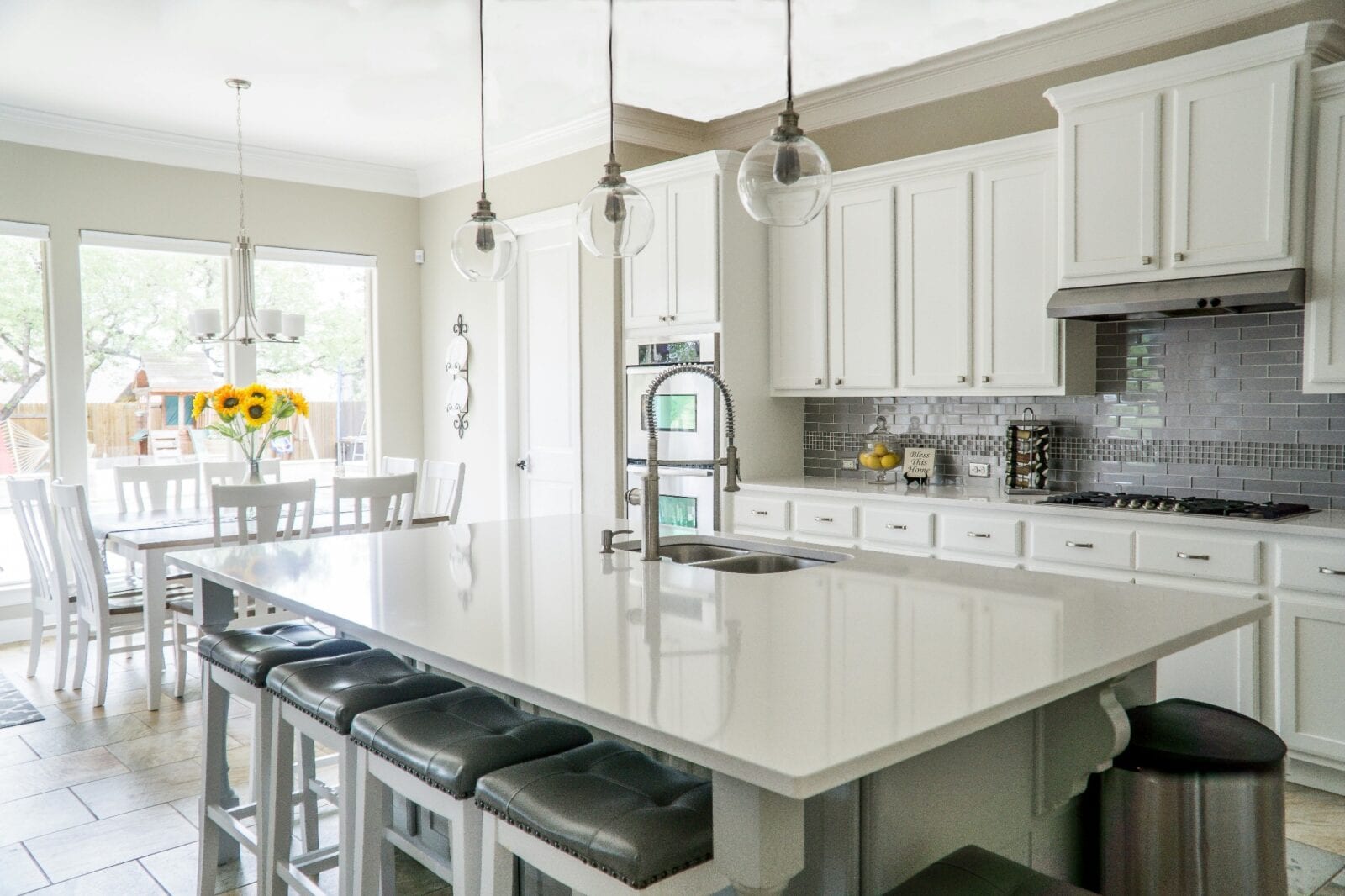 Bright white kitchen with a large island and a vase of sunflowers by the window