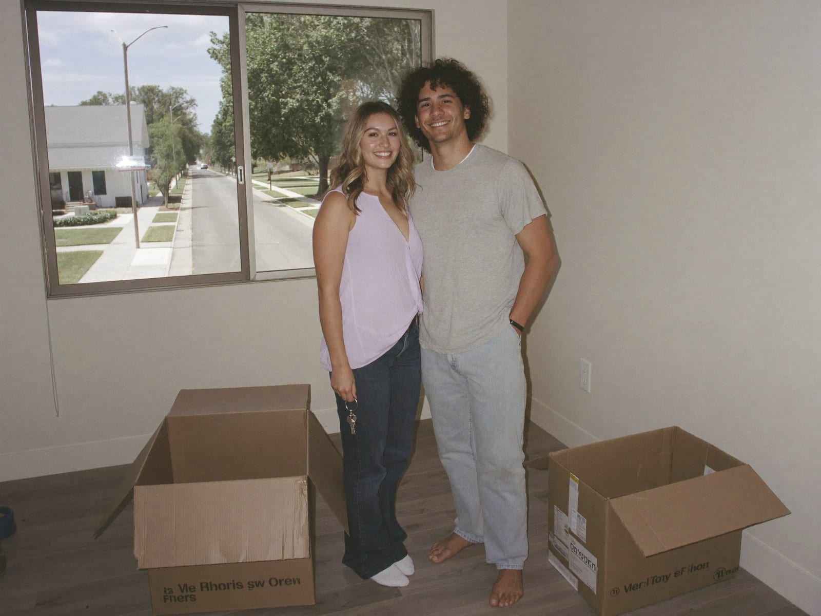 A couple standing among moving boxes in an empty room