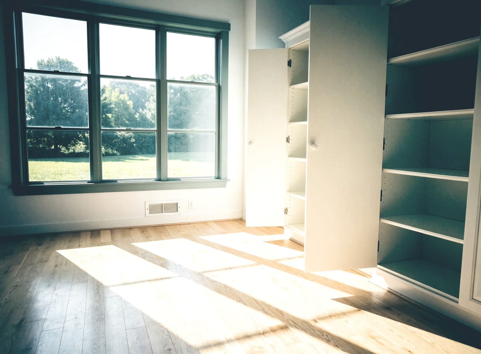 Empty room with a large window and built-in shelving after a move-out clean